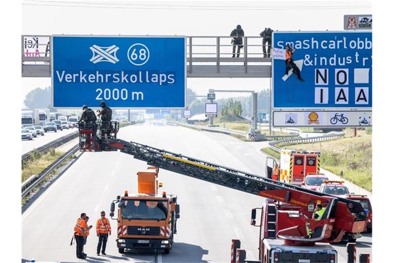 Ein Aktivist hängt während einer Banneraktion an einer Schilderbrücke über der Autobahn A9 bei Fürholzen in Fahrtrichtung München. Foto: Matthias Balk/dpa