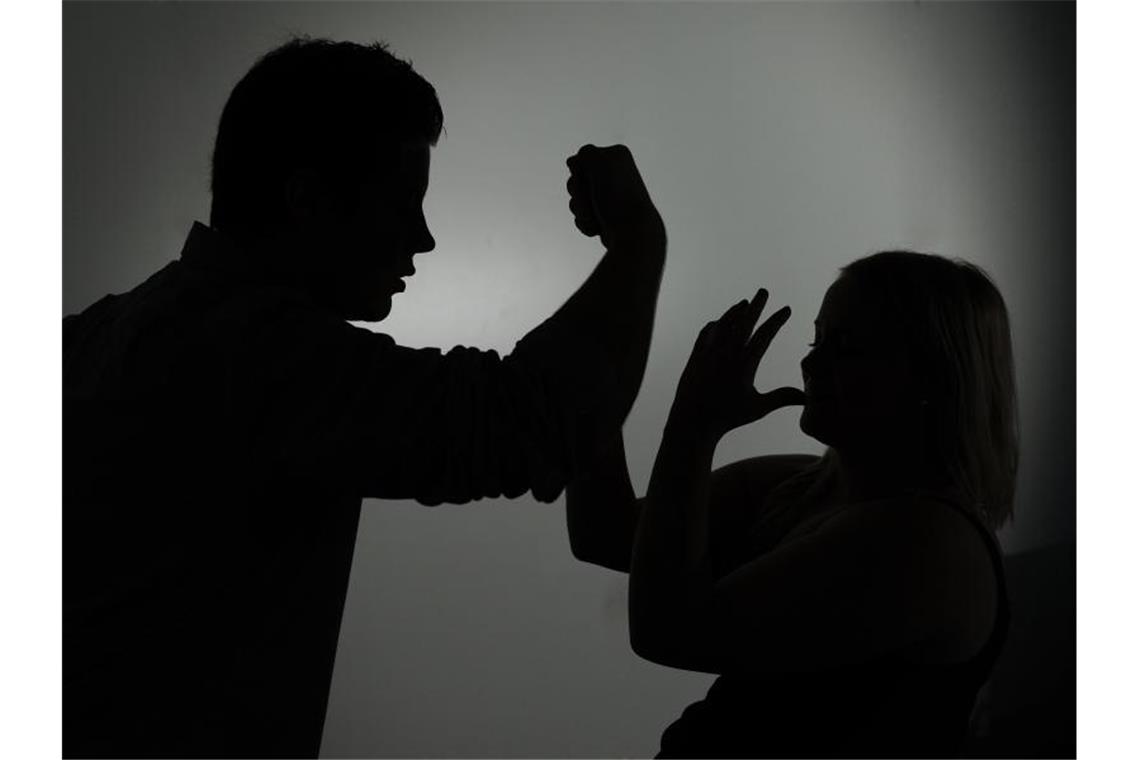 Ein als Silhouette abgebildeter Mann droht einer Frau mit der Faust. Foto: Jan-Philipp Strobel/dpa/Symbolbild