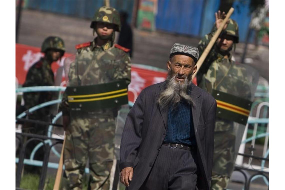 Neue Dokumente: Willkürliche Inhaftierung von Uiguren Ein Angehöriger der uigurischen Minderheit in der Unruheregion Xinjiang geht an chinesischen Sicherheitskräften vorbei. Foto: Diego Azubel/epa/dpa