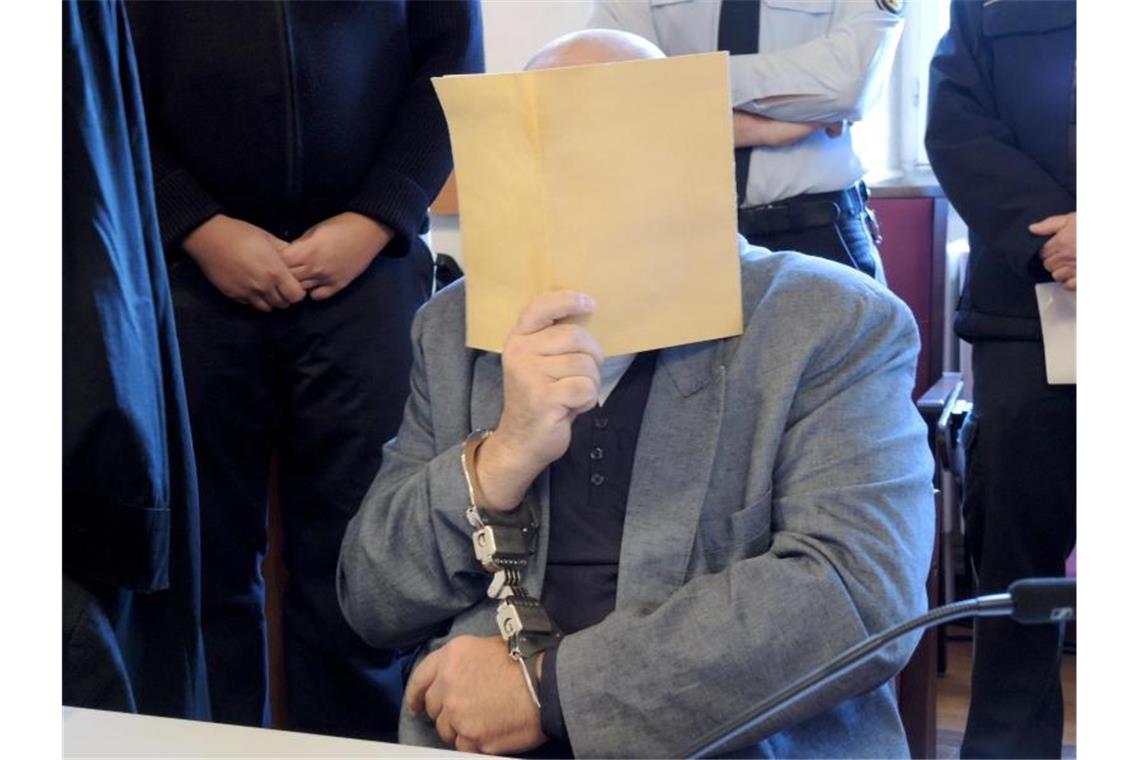 Urteil gegen Vater im Ellwanger Mordprozess erwartet Ein Angeklagter sitzt mit einem Aktendeckel zum Schutz vor Fotos im Gerichtssaal. Foto: Thomas Burmeister/dpa