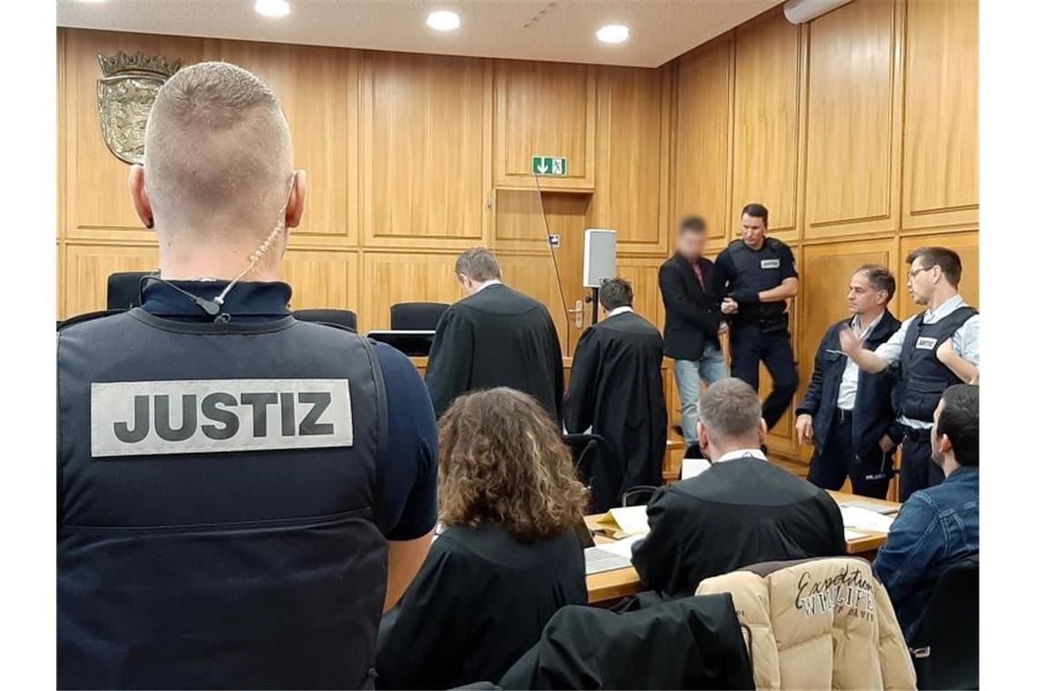 Feuer in der Döner-City: Imbiss-Besitzer vor Gericht Ein Angeklagter wird vor dem Beginn der Verhandlung in einen Gerichtssaal geführt. Nach dem Brand in einem Imbiss in Heilbronn stehen die frühere Pächterin, der Betreiber und zwei Komplizen wegen mutmaßlicher Brandstiftung vor Gericht. Foto: Martin Oversohl/dpa