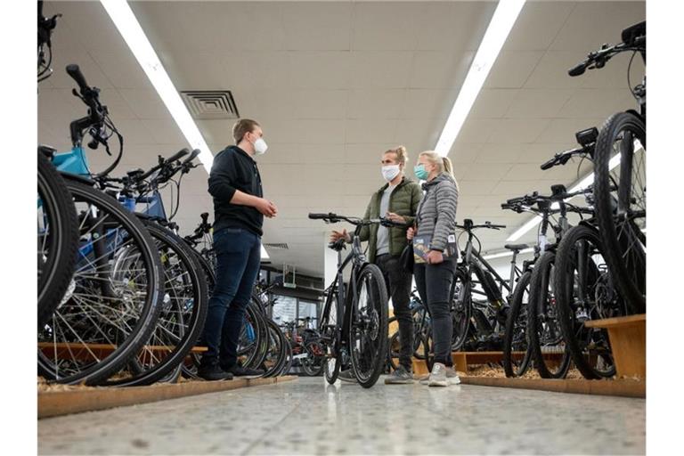 Ein Angestellter eines Fahrradlades berät in einem Verkaufsraum Kunden. Foto: Marijan Murat/dpa