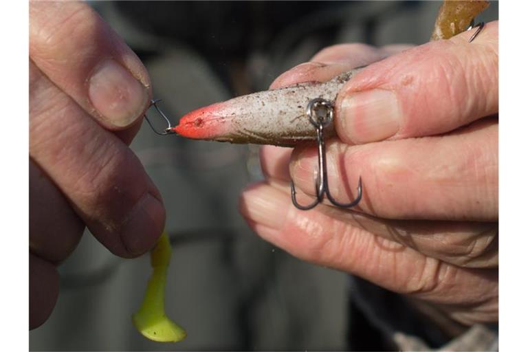 Ein Angler bereitet seine Angel vor und hängt einen Drilling an die Angelschnur. Der Fischereiverband beschäftigt sich derzeit mit dem Kliamwandel. Foto: Klaus-Dietmar Gabbert