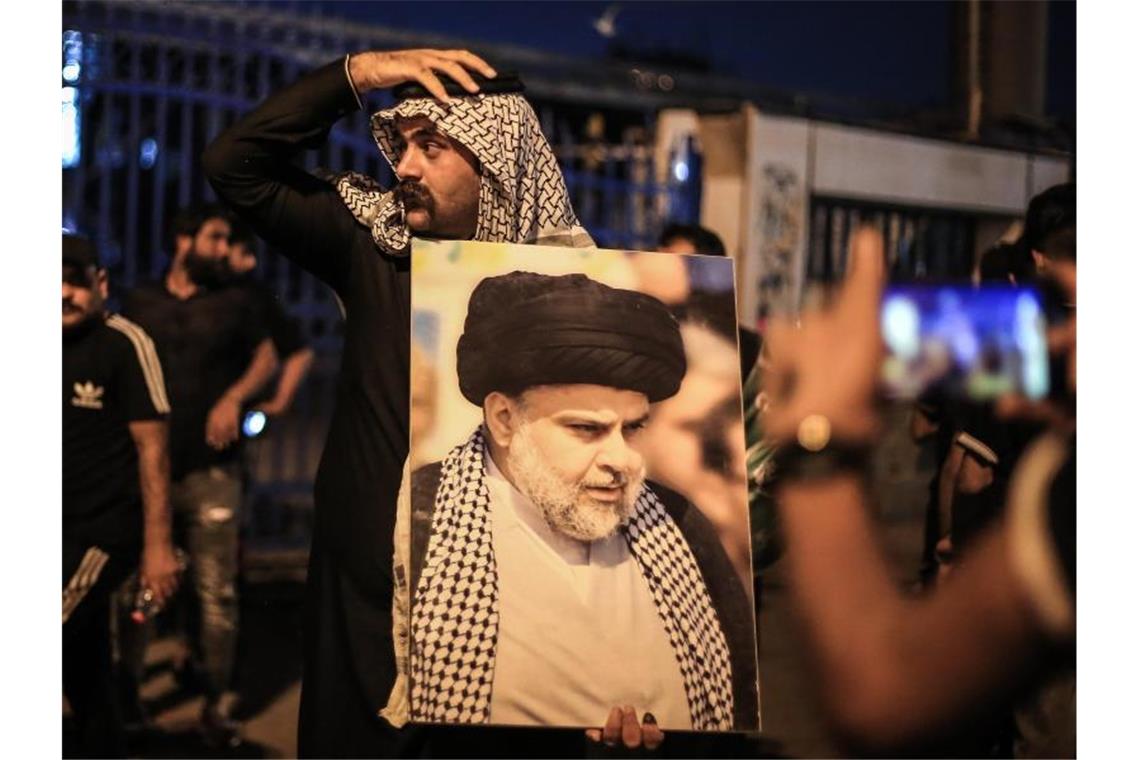 Ein Anhänger des irakischen schiitischen Geistlichen al-Sadr jubelt auf dem Tahrir-Platz nach der Bekanntgabe der Ergebnisse der Parlamentswahlen. Foto: Ameer Al Mohammedaw/dpa