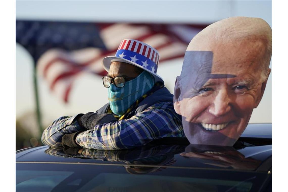 Ein Anhänger des Präsidentschaftskandidaten der Demokraten Biden schaut sich eine Wahlkampfveranstaltung von Joe Biden und und dem ehemaligen Präsidenten Barack Obama an. Foto: Andrew Harnik/AP/dpa