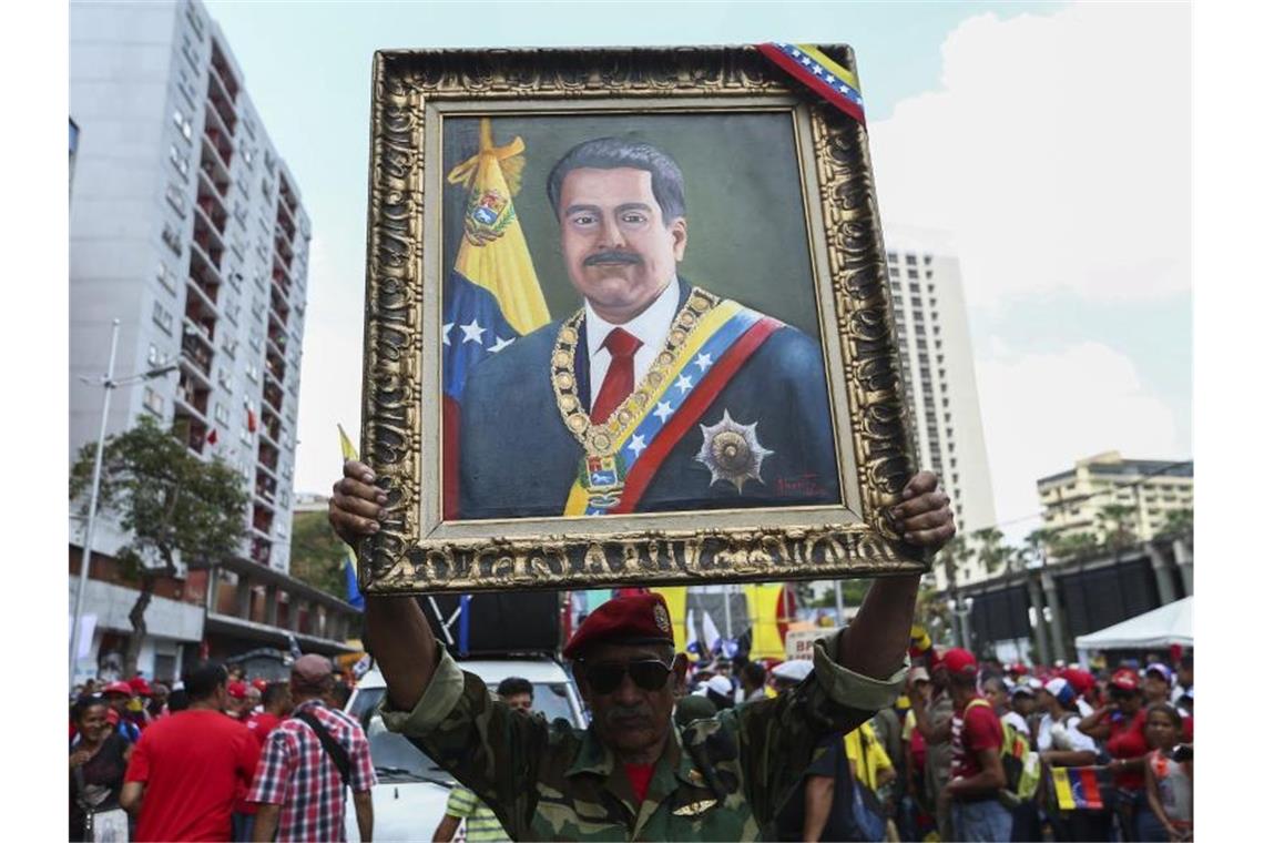 Neue Sanktionen - Trump erhöht den Druck auf Venezuela Ein Anhänger von Maduro mit einem Porträt des venezolanischen Präsidenten. Foto: Pedro Mattey