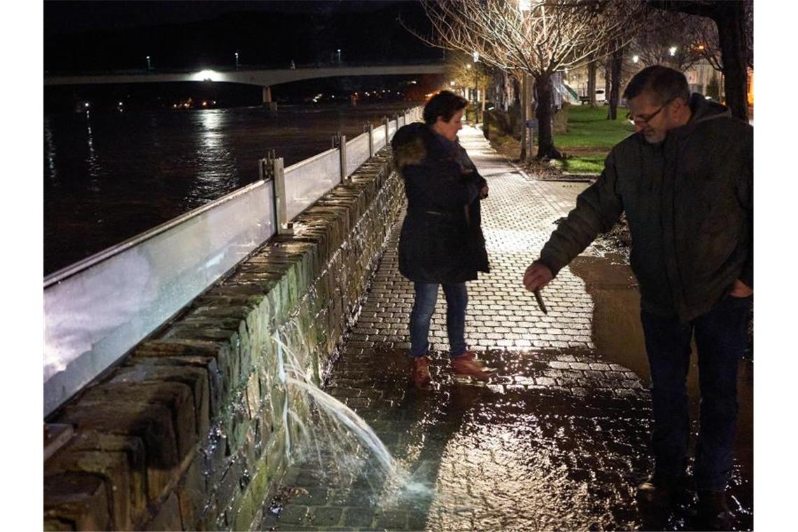 Ein Anwohner filmt mit seinem Handy in Zell eine Stelle an der Hochwasserschutzmauer, an der das Wasser der Mosel durch die Wand dringt. Foto: Thomas Frey/dpa