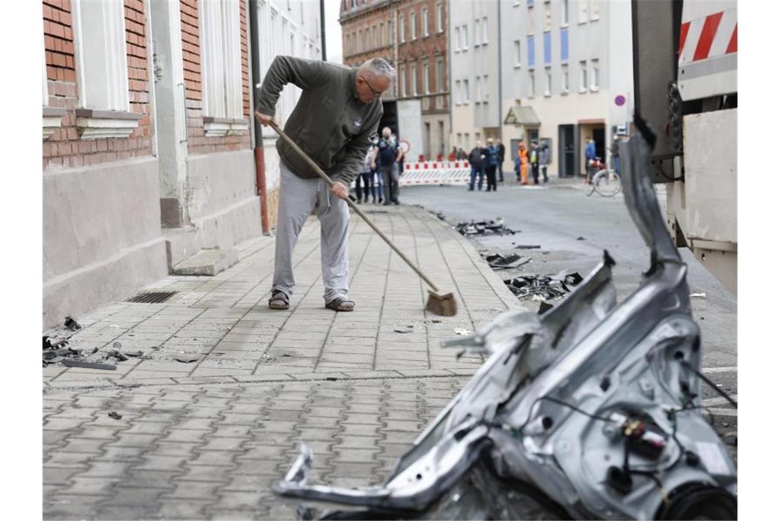 Lkw verwüstet Wohnstraße - „Sieht aus wie nach einem Krieg“ Ein Anwohner kehrt am Tag nach der Chaosfahrt den Bürgersteig vor seinem Haus. Foto: Löb Daniel/dpa