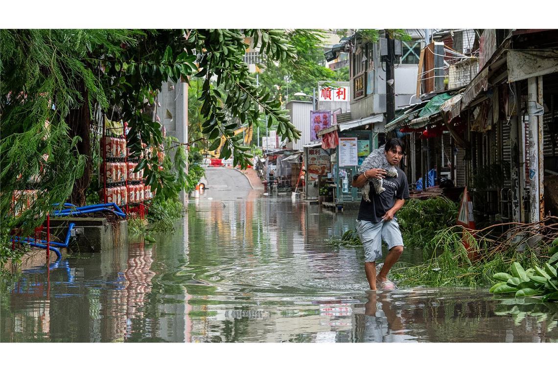 Nach Super-Taifun "Ragasa": Neuer Sturm im Anmarsch Ein Anwohner trägt in Hongkong ein Haustier durch das Hochwasser.