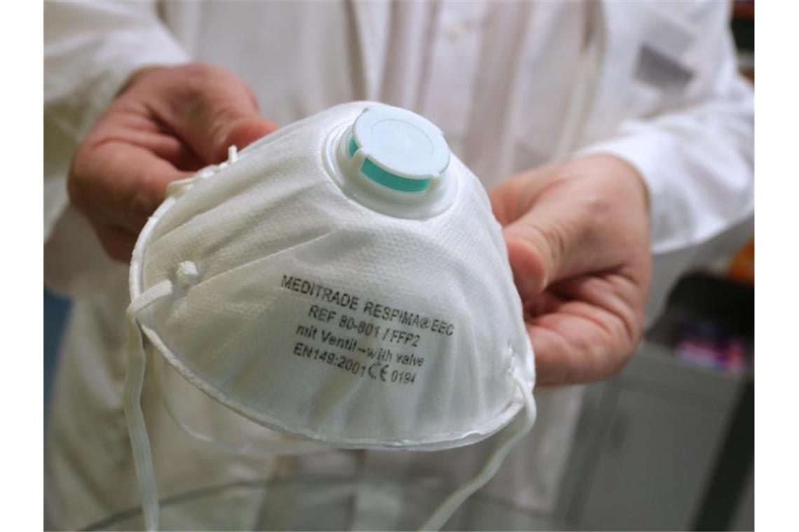 Ärzte warnen vor Ansturm auf Praxen wegen Coronavirus Ein Apotheker hält eine Atemschutzmaske. Foto: Karl-Josef Hildenbrand/dpa/Archivbild