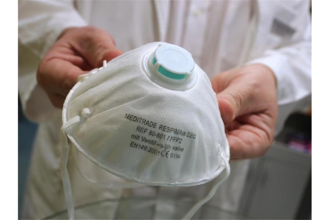 Autobauer spenden Atemschutzmasken an Kliniken und Behörden Ein Apotheker hält in einer Apotheke eine FFP2 Atemschutzmaske. Foto: Karl-Josef Hildenbrand/dpa/Archivbild