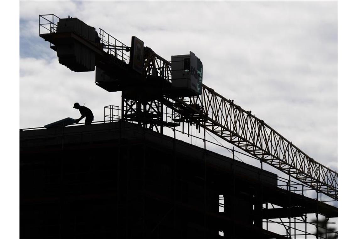 Ein Arbeiter arbeitet auf dem Dach eines Rohbaus in einem neuen Wohnquartier in Hannover. Foto: Julian Stratenschulte/dpa