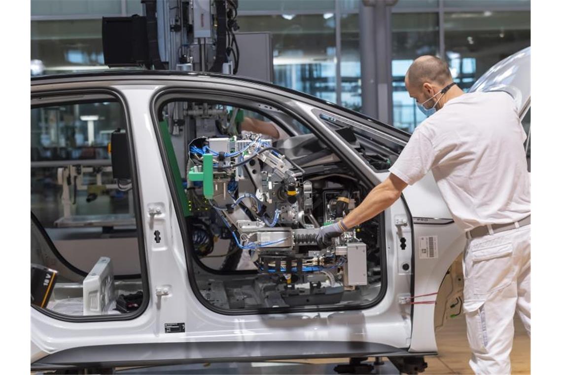 Ein Arbeiter arbeitet mit Mund-Nasen-Schutz an einem Auto. Foto: Matthias Rietschel/dpa-Zentralbild/dpa