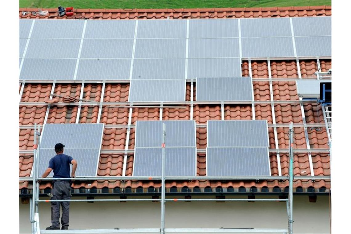 Ein Arbeiter installiert auf einem Dach eine Solaranlage. Foto: Rolf Haid/dpa/Archivbild