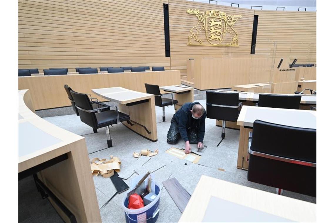 Ein Arbeiter ist im Plenarsaal im Landtag mit dem Umbau der Sitzreihen beschäftigt. Foto: Bernd Weißbrod/dpa