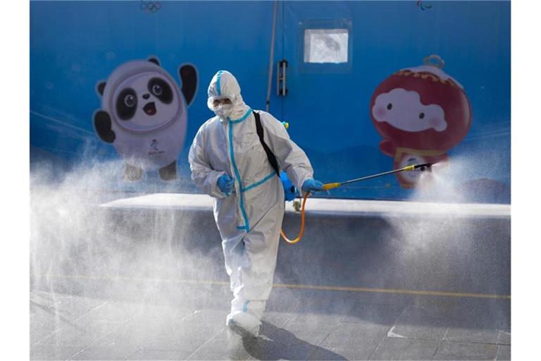 Ein Arbeiter versprüht Desinfektionsmittel vor einem Hotel in Peking. Foto: Natacha Pisarenko/AP/dpa