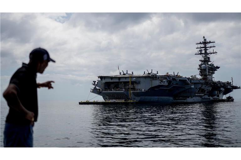 Ein Arbeiter zeigt auf den Flugzeugträger USS Nimitz der U.S. Navy, der im Golf von Panama andockt.