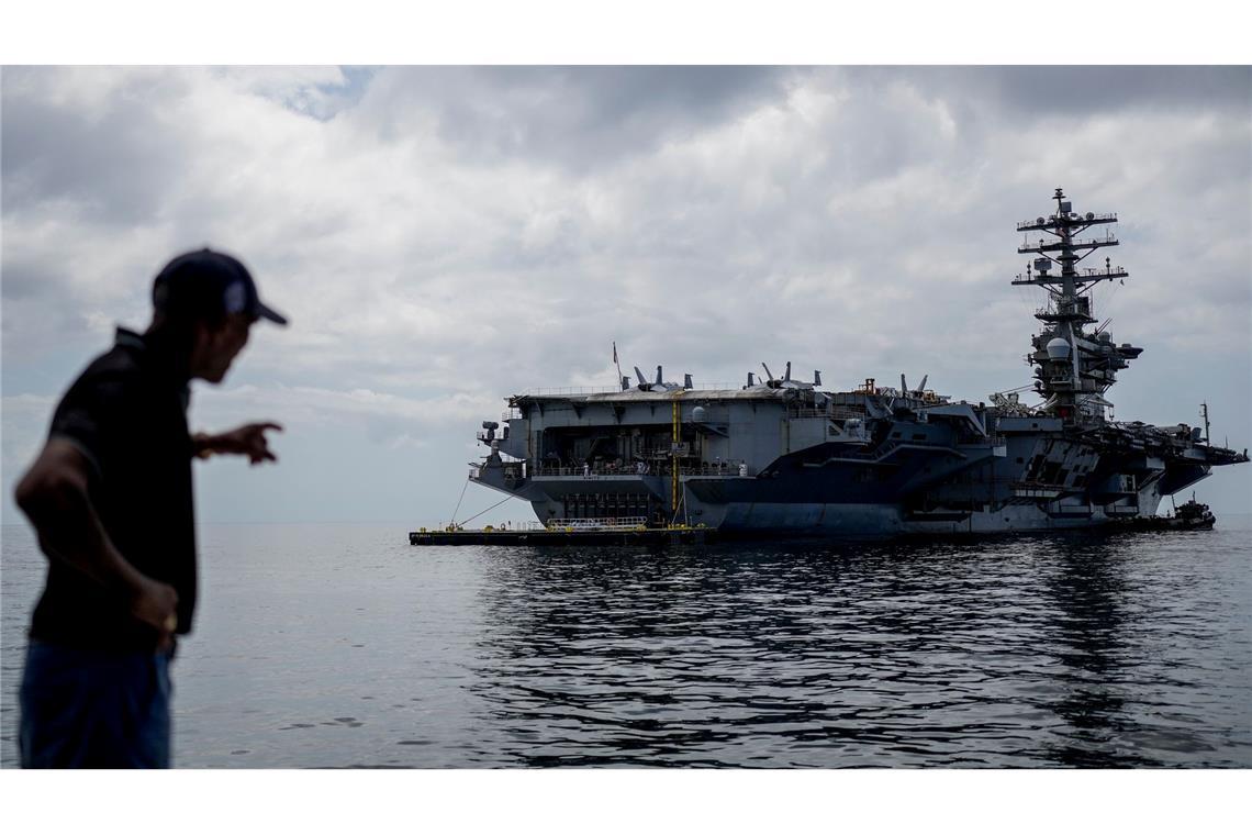 Ein Arbeiter zeigt auf den Flugzeugträger USS Nimitz der U.S. Navy, der im Golf von Panama andockt.