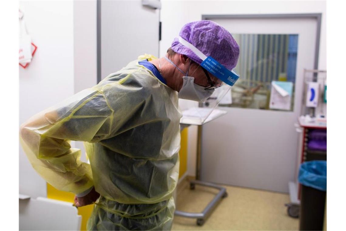 RKI blickt detailliert auf Covid-19-Patienten mit Symptomen Ein Arzt des Krankenhauses Düren zieht seine Schutzkleidung an, um auf der Intensivstation des Krankenhauses Düren einen Covidpatienten zu untersuchen. (Archivbild). Foto: Thomas Banneyer/dpa