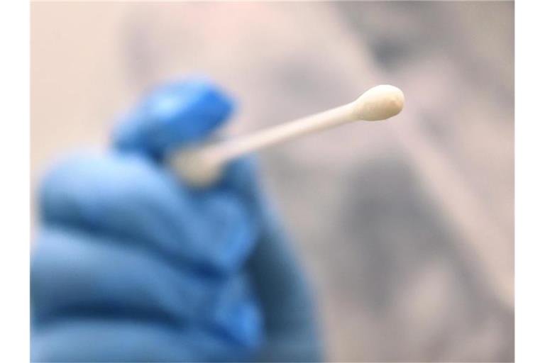 Ein Arzt hält einen Tupfer, mit dem ein Abstrich für einen Coronatest gemacht wird. Foto: Karl-Josef Hildenbrand/dpa/Symbolbild