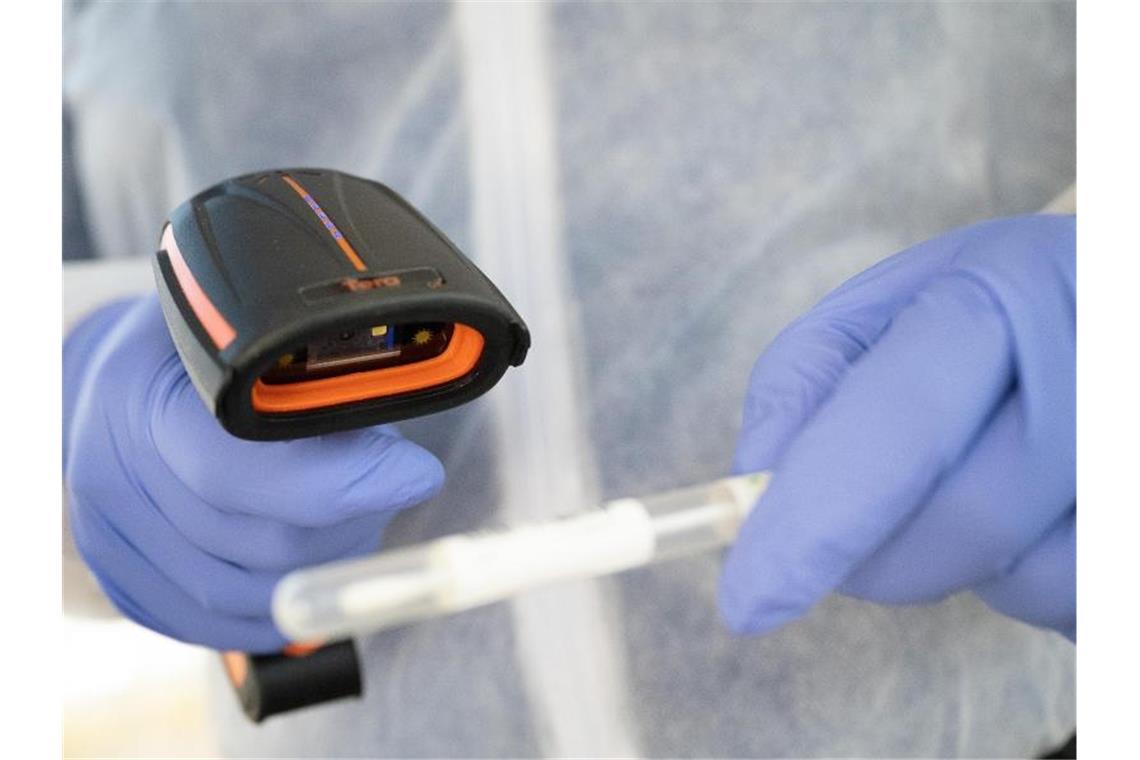 Ein Arzt in Schutzkleidung scannt ein Teststäbchen in einer mobilen Corona-Teststation. Foto: Sebastian Gollnow/dpa