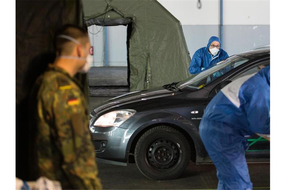 Bundeswehr setzt in der Corona-Krise 15.000 Soldaten ein Ein Arzt nimmt bei einer von der Bundeswehr organisierten Drive-In-Teststation in Saarbrücken Abstriche. Foto: Oliver Dietze/dpa