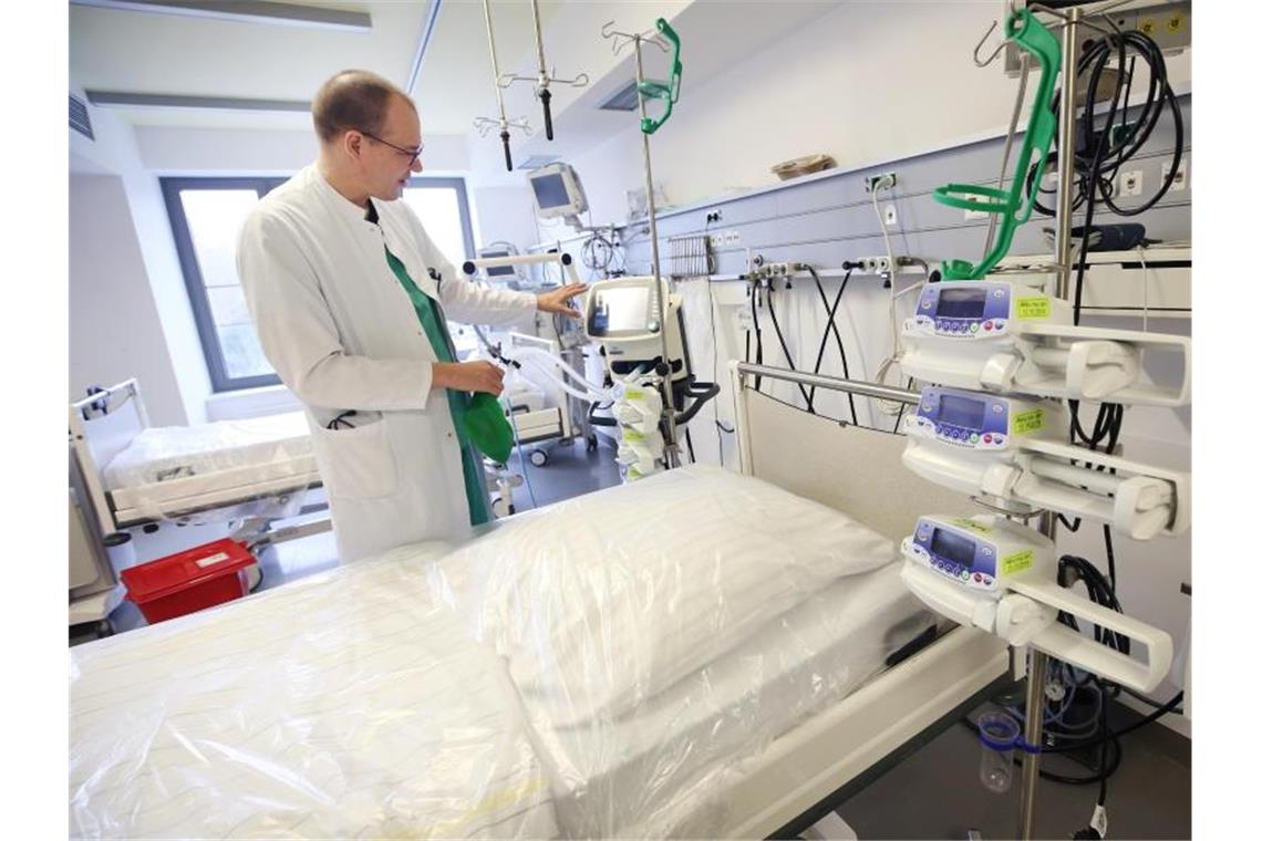 Ein Arzt steht neben einem Intensivbett im Krankenhaus. Foto: Roland Weihrauch/dpa/Symbolbild