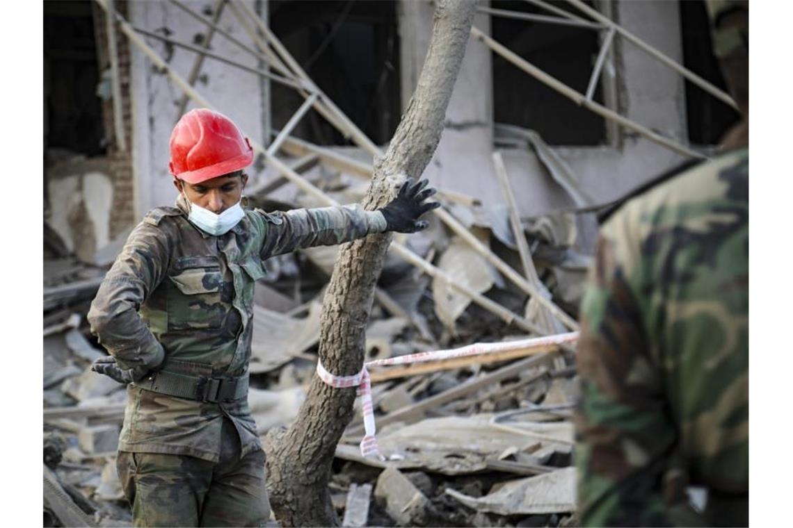 Ein aserbaidschanischer Soldat steht in der Nähe eines zerstörten Hauses in einem Wohngebiet, das von armenischen Streitkräften durch Raketenbeschuss getroffen wurde. Foto: Aziz Karimov/AP/dpa