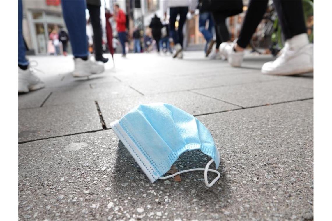 Ein auf dem Boden liegender Mund-Nasen-Schutz in der Kölner Innenstadt. Der Bund will eine ergänzende Maskenpflicht einführen. Foto: Weronika Peneshko/dpa
