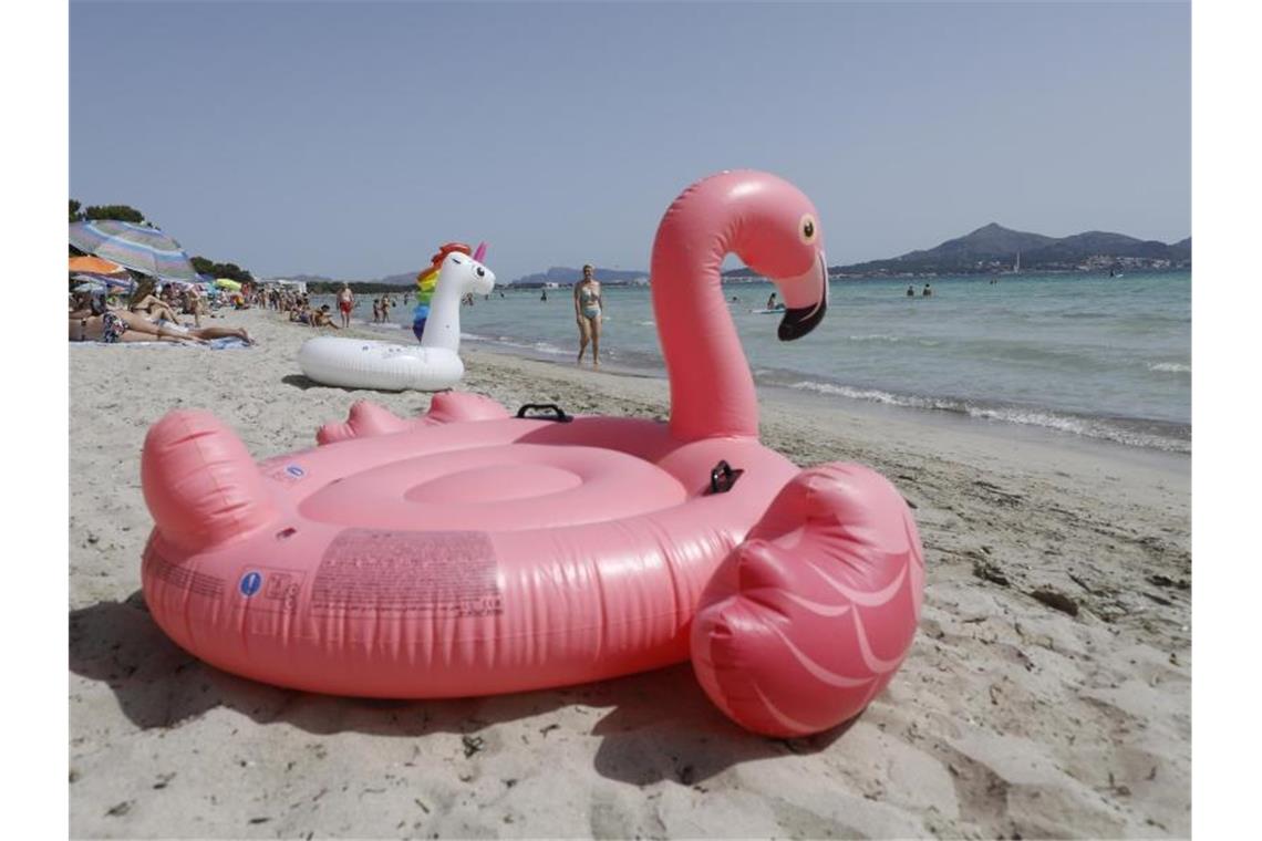 Ein aufblasbarer rosa Flamingo liegt am Strand von Playa de Muro im Norden von Mallorca. Foto: Clara Margais/dpa