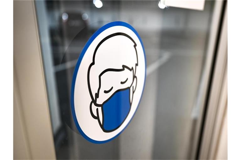 Ein Aufkleber an einer Glastür weist auf das Tragen einer Maske hin. Foto: Felix Kästle/dpa/Symbolbild