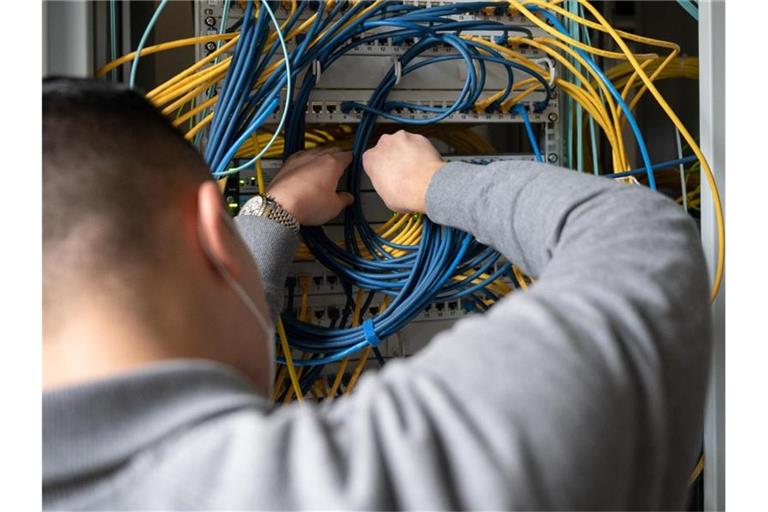 Ein Auszubildender Fachinformatiker Systemintegration bei der IHK Region Stuttgart im 2. Ausbildungsjahr, steckt an einem Server ein Netzwerkkabel ein. Foto: Sebastian Gollnow/dpa