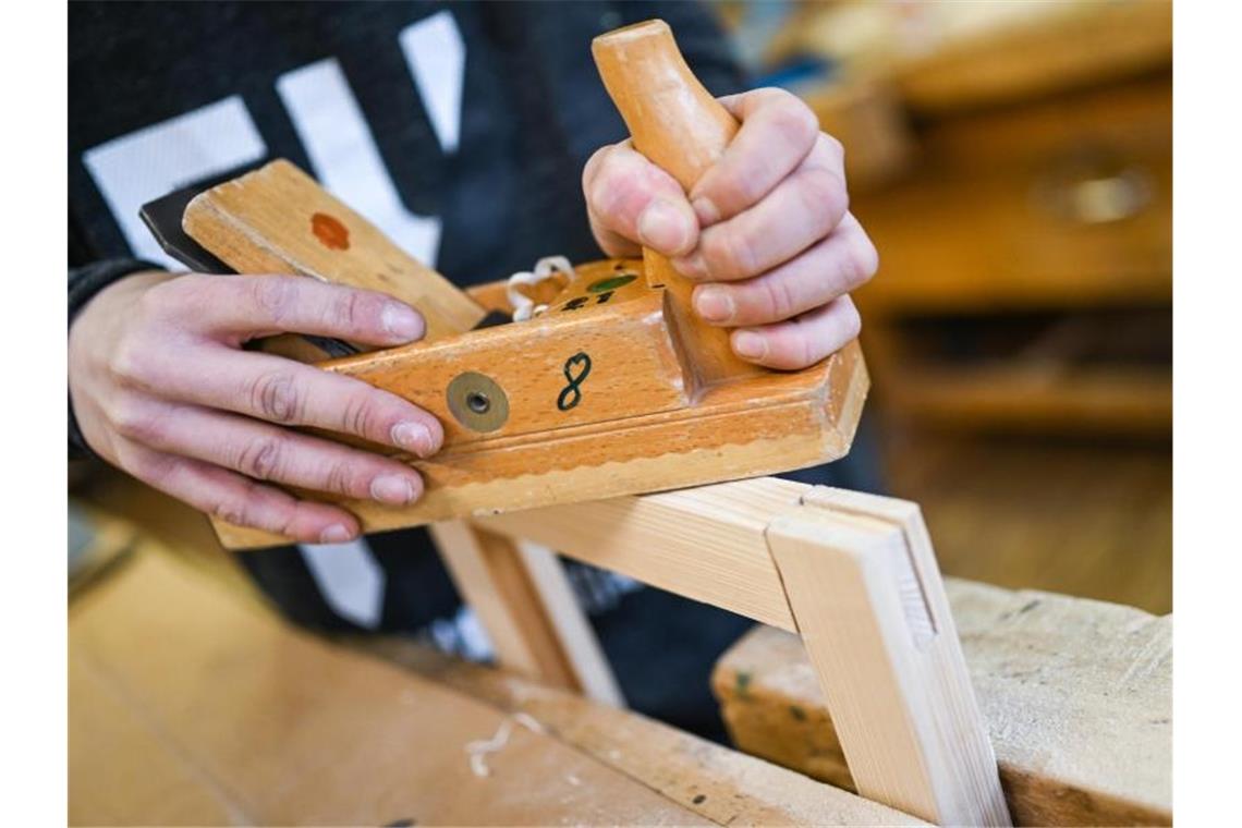 Ein Auszubildender im Schreiner-Handwerk arbeitet an seinem Werkstück. Foto: Felix Kästle/dpa/Archivbild