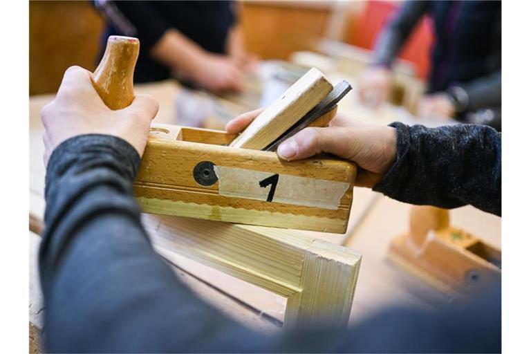 Ein Auszubildender im Schreiner-Handwerk arbeitet in einem Ausbildungszentrum mit dem Hobel an seinem Werkstück. Foto: Felix Kästle/dpa/Archivbild