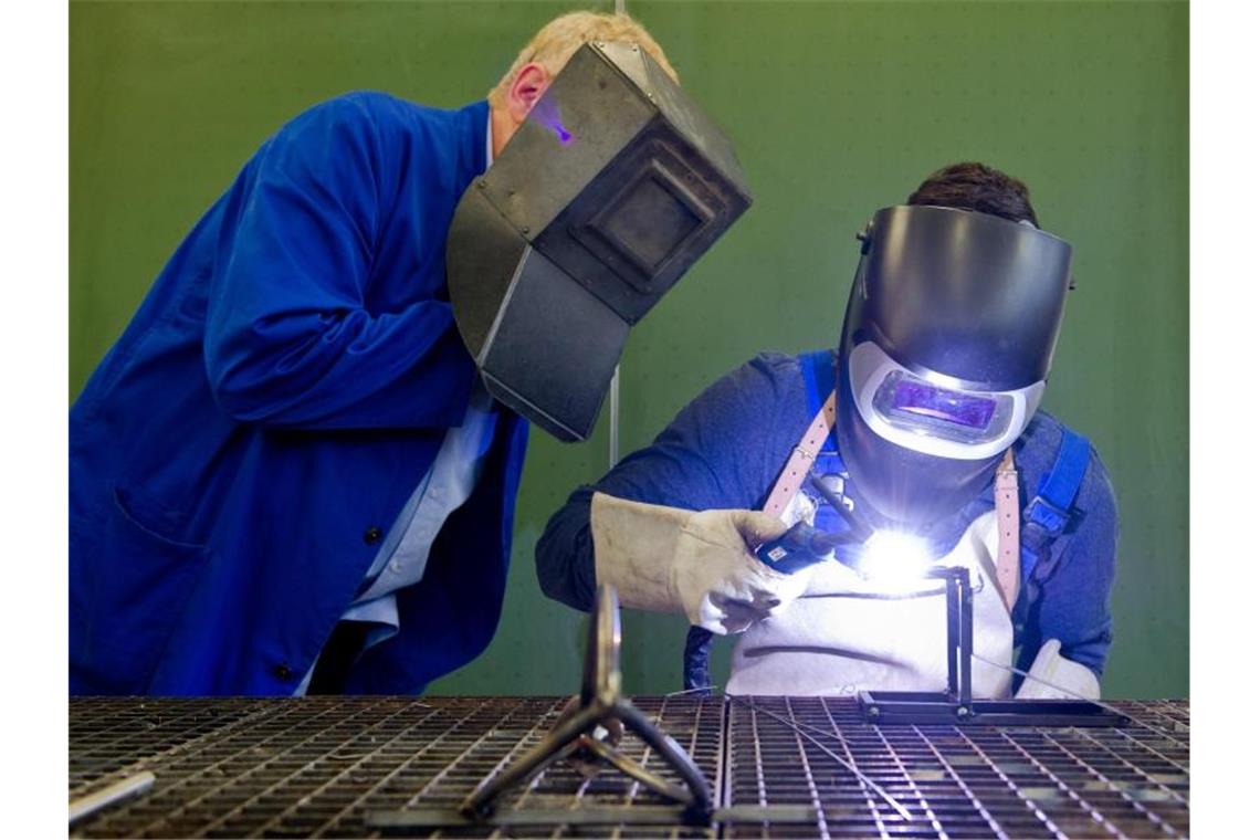 Deutlich weniger Ausbildungsplätze im Südwesten Ein Auszubildender setzt eine Schweißnaht an ein Metallteil, während ein Berufsschullehrer zuschaut. Foto: Daniel Bockwoldt/dpa/Symbolbild