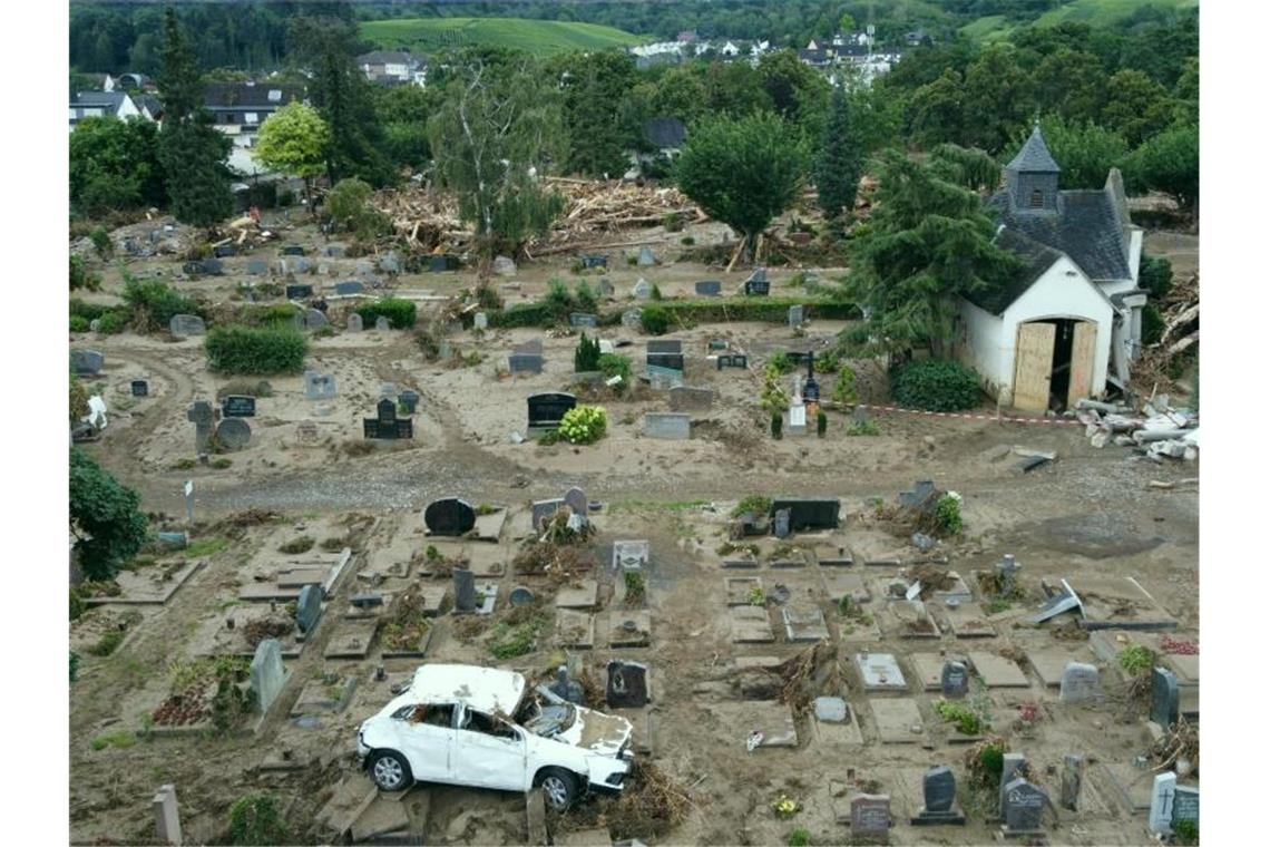 Ein Auto, das bei der Hochwasserkatastrophe auf den Friedhof geschwemmt worden ist, steht auf einem Grabfeld. Der Friedhof ist völlig zerstört. Foto: Thomas Frey/dpa