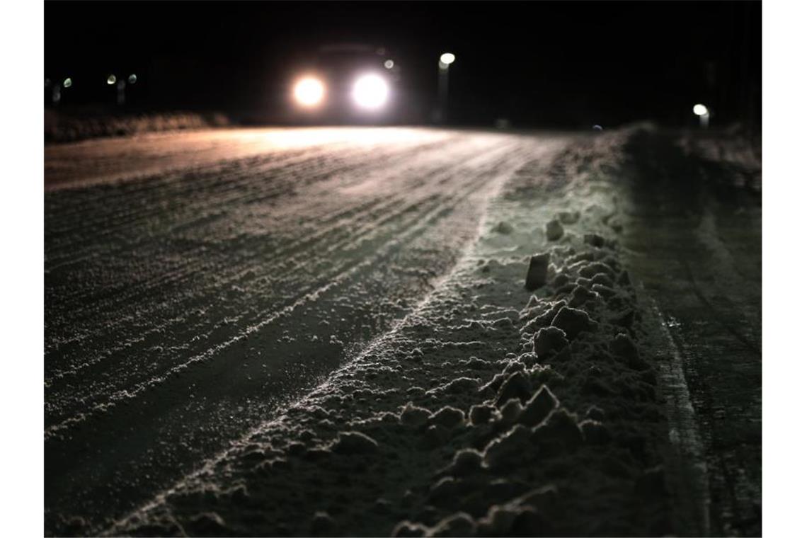 Ein Auto fährt am frühen Morgen über eine schneebedeckte Straße im südbayrischen Marktoberdorf. Foto: Karl-Josef Hildenbrand/dpa