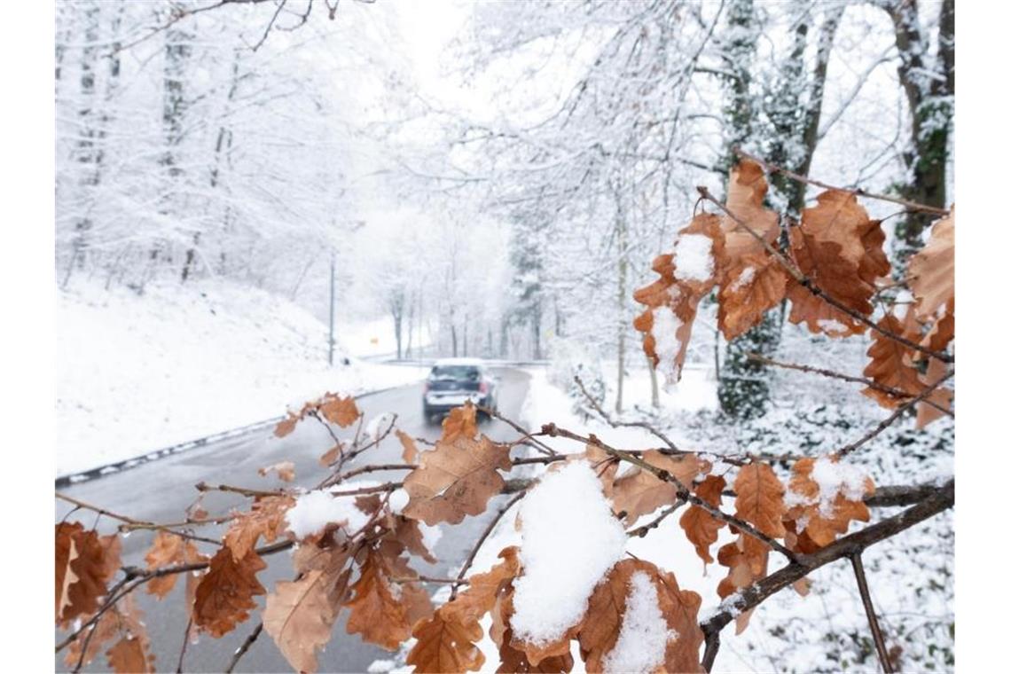 Ein Auto fährt auf einer Straße durch eine Schneelandschaft. Foto: Bernd Weißbrod/dpa