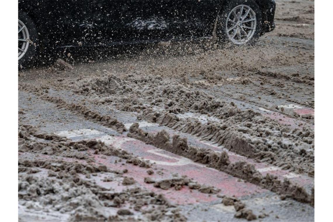 Viele Unfälle nach Wintereinbruch Ein Auto fährt auf einer Straße durch Schneematsch. Foto: Marijan Murat/dpa
