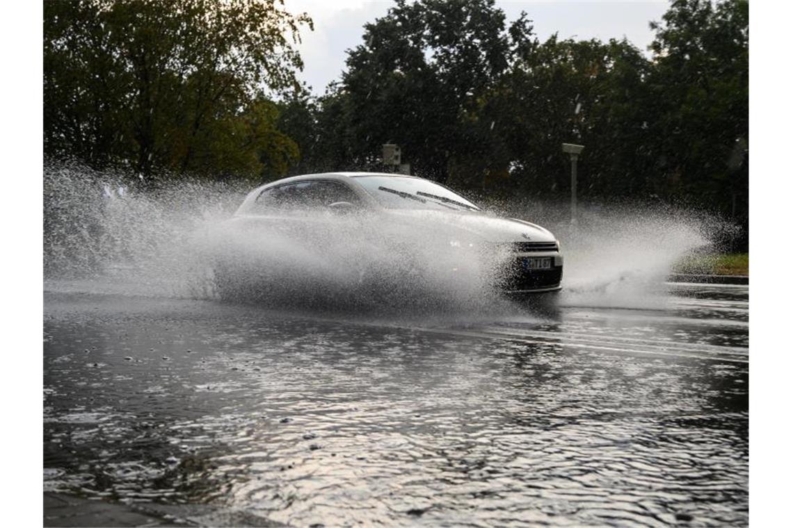 Ein Auto fährt bei starkem Regen über eine überschwemmte Straße in Hannover. Foto: Christophe Gateau