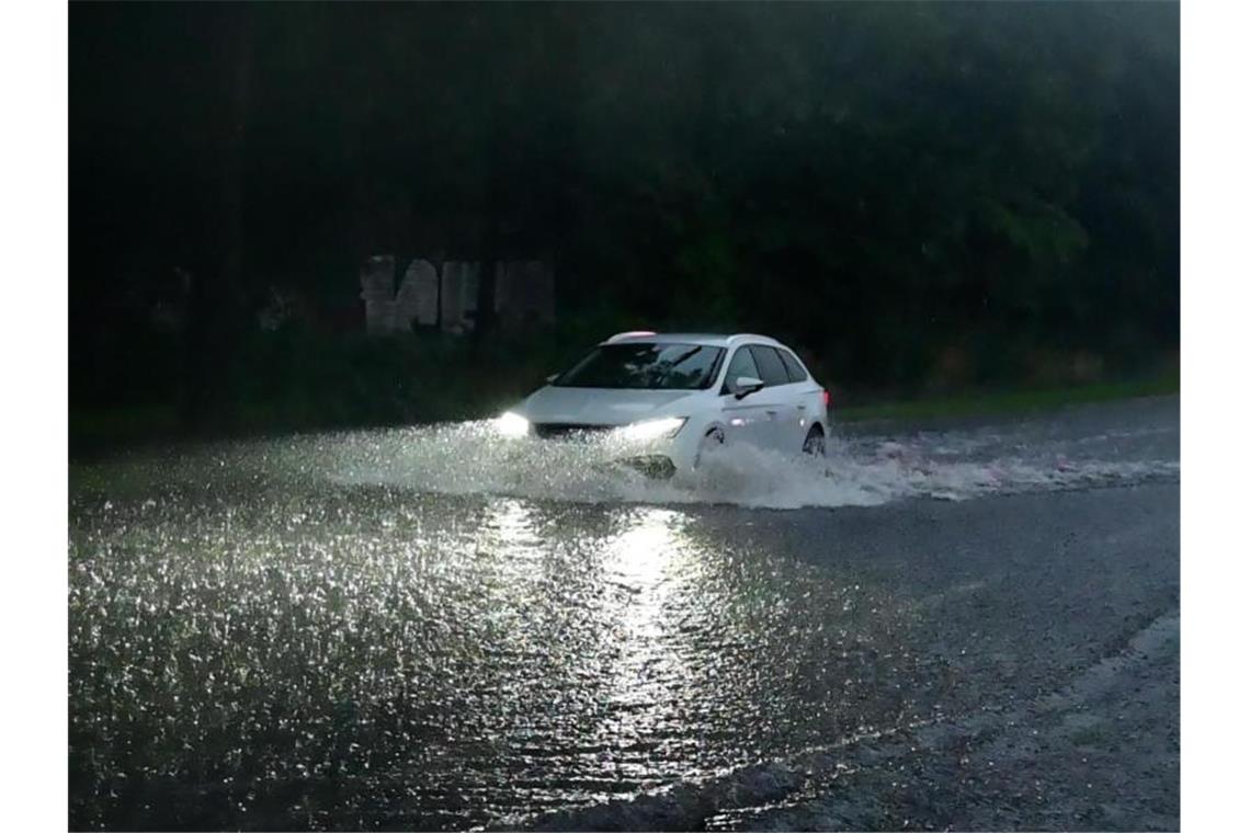 Ein Auto fährt durch eine überflutete Straße. Foto: Alexander Forstreuter/Photography Alex Forstreuter/dpa/Symbolbild