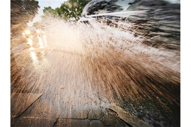 Ein Auto fährt durch eine Wasserlache auf der Straße. Foto: Martin Gerten