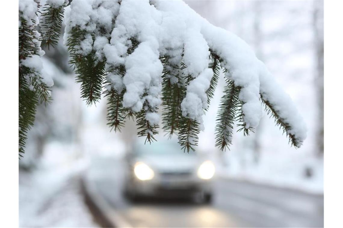 Wintergewitter sorgt für Verkehrschaos in Baden-Württemberg Ein Auto fährt hinter einem schneebedeckten Zweig über die Straße. Foto: Matthias Bein/dpa-Zentralbild/dpa/Symbolbild