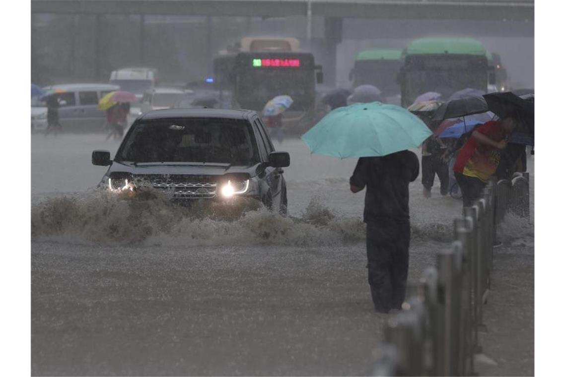 Überschwemmungen stürzen chinesische Metropole ins Chaos Ein Auto fährt in der zentralchinesischen Provinz Henan über eine überflutete Straße. Foto: Yuanxiaoqiang/CHINATOPIX/AP/dpa
