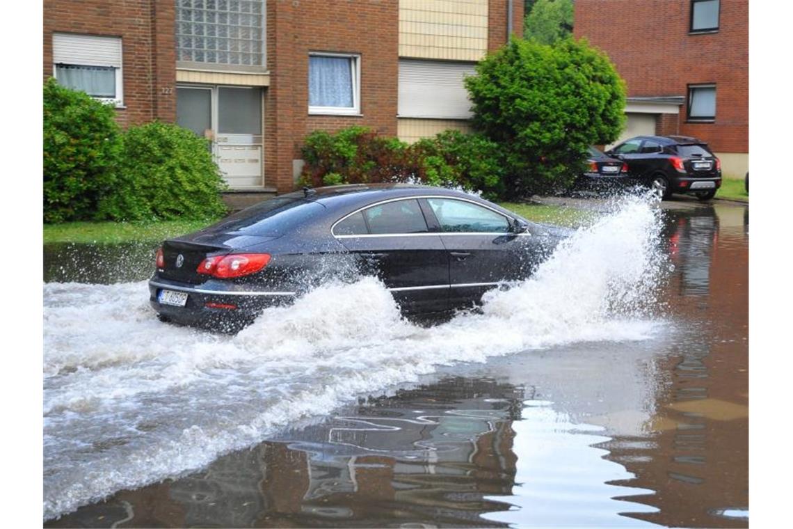 Heftige Gewitter über München Ein Auto fährt nach heftigen Regenfällen durch eine überflutete Straße in Mönchengladbach. Foto: Theo Titz