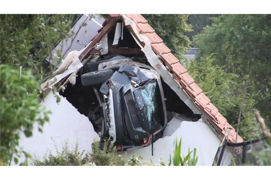 Ein Auto liegt nach einem kurzen Flug seitlich in der Mauer einer Scheune.