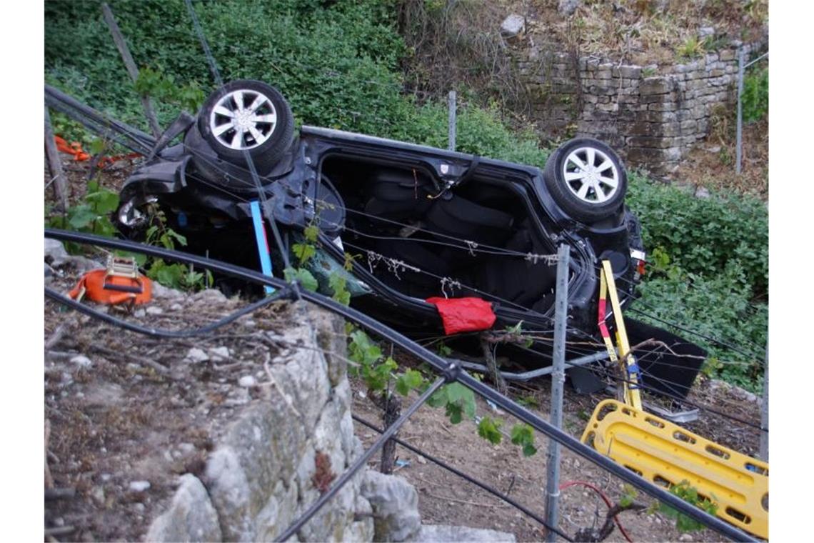 Ein Auto liegt nach einem Unfall in einem Steilhang in einem Weinberg. Foto: Hemmann/SDMG/dpa