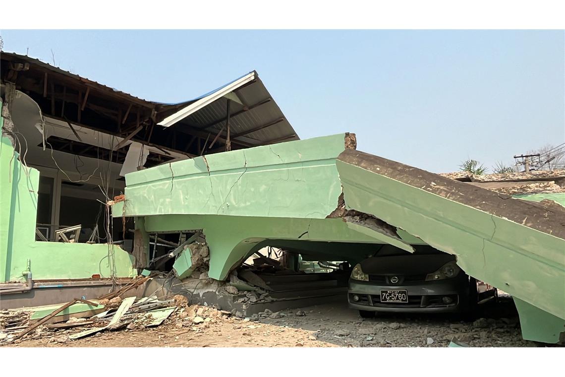 Ein Auto steckt unter einem zerstörten Gebäude in Myanmar fest.