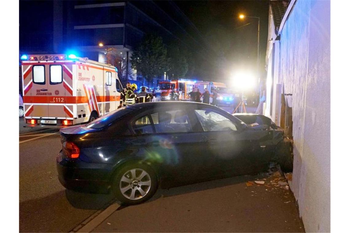 Ein Auto steht im Licht von Feuerwehrscheinwerfern an einer Mauer, gegen die er gefahren ist. Foto: Andreas Rosar