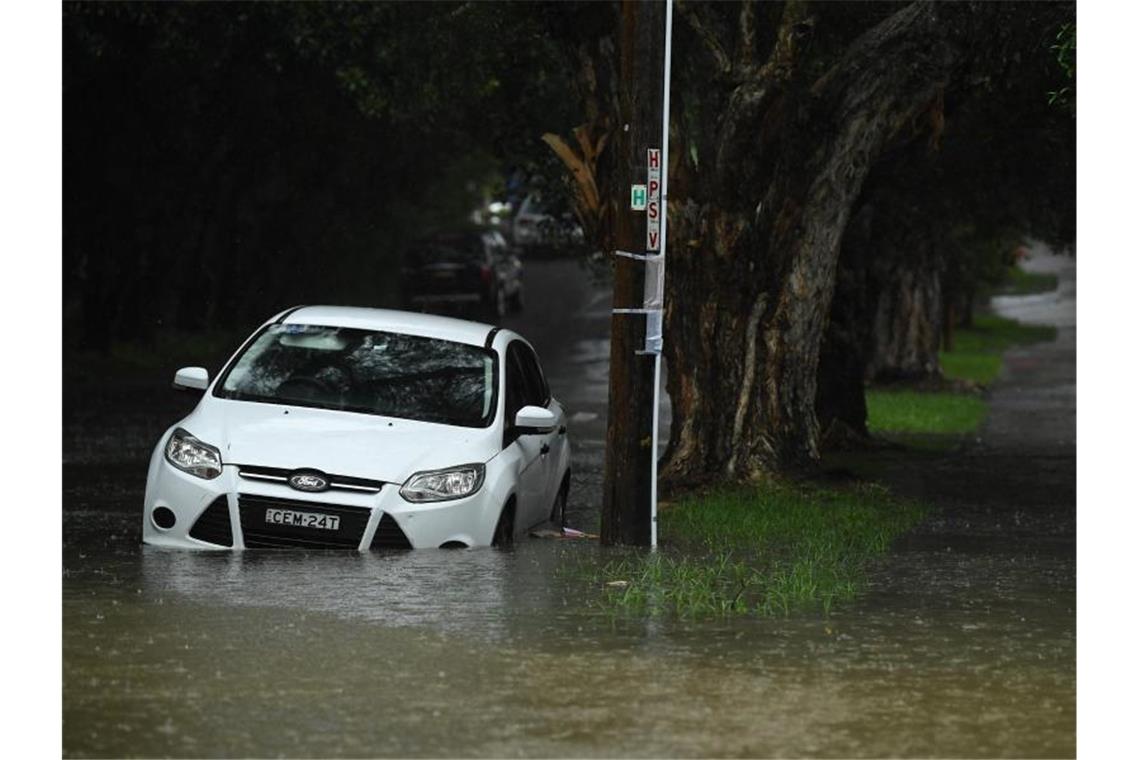 Ein Auto steht in einer überfluteten Straße in Sydney. Schwere Unwetter haben weite Teile Australiens heimgesucht. Foto: Joel Carrett/AAP/dpa